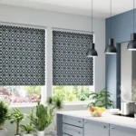 A kitchen with Two windows covered by patterned roller blinds.