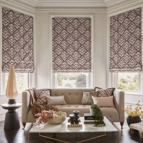 A well-decorated room with a neutral color palette. The light-filtering fabric of the Roman blinds