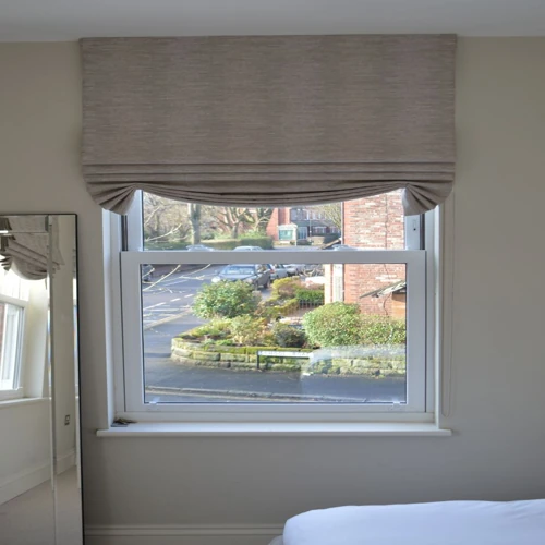 Window with a taupe textured Swaged Roman blind pulled up to show a soft curved.